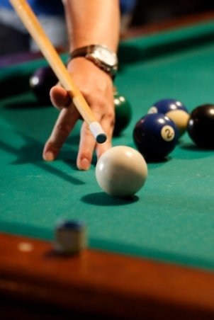 Man playing billiards about to hit the cue ball