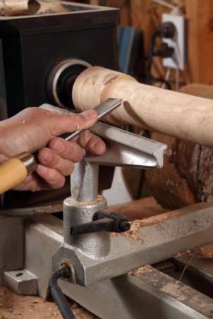Man carving a table leg on a wood lathe