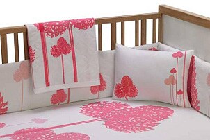 Baby mattress in a crib with pink and white bedding