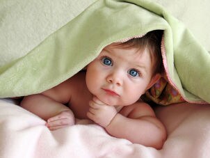 Cute baby girl under a blanket in a baby crib