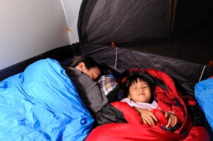 Father and son camping in sleeping bags