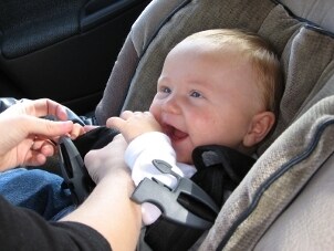 Smiling baby being buckled into a car seat
