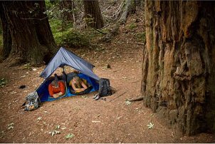 Couple camping in sleeping bags and a tent