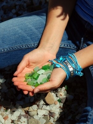 A woman wearing layers of crystal turquoise bracelets and holding green rocks