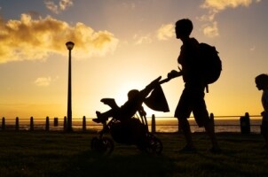 Woman pushing a baby stroller at sunset