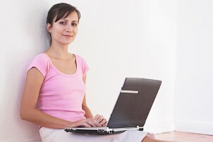 Woman sitting with a notebook computer on the floor