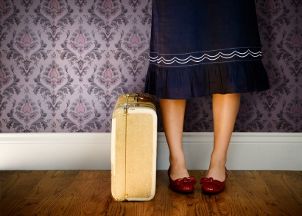Woman wearing a navy blue skirt standing by suitcase