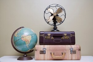 Retro fan on old-fashioned suitcases next to globe