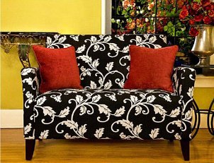 Cream loveseat with sage green textured decorative pillows and wooden legs