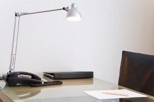 Minimalist home office with black chair, desk phone and silver desk lamp