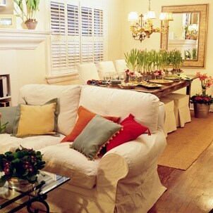 Living and dining room with elegant home decor, including flowers, mirrors, a chandelier and throw pillows