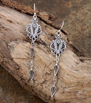 A pretty pair of dangling chandelier earrings on a log