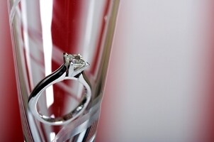 A princess-cut diamond engagement ring in a champagne flute