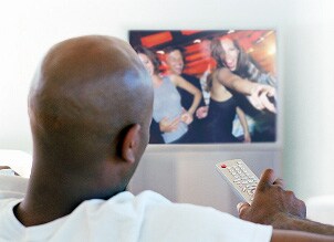 Man holding a remote watching his HD television
