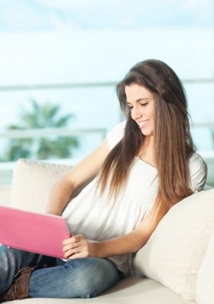 Woman in jeans and shirt works on her laptop