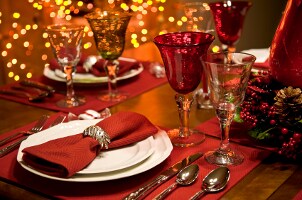 A pretty holiday table is set with wine glasses, dishes and flatware