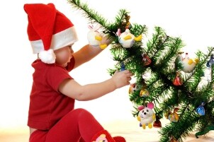 Baby pulling over a Christmas tree decorated with baby toys
