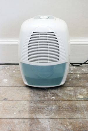 White dehumidifier dries out air in unfinished basement