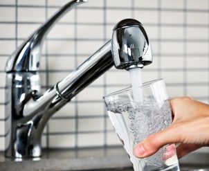 Woman fills water glass from a tap water filter