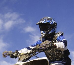 Mud-splattered motorcycle rider in motorcycle helmet