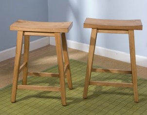 Two black wooden bar stools in a blue room with a green rug