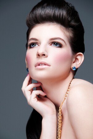An elegant model wearing gold chains and blue gemstone earrings
