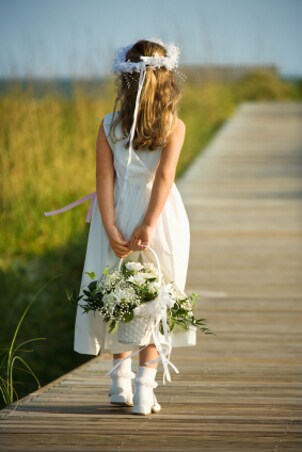 Cute flowergirl wearing a white dress and shoes at a wedding